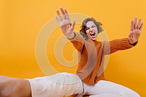 Blissful caucasian girl laughing on yellow background and waving hands. Studio shot of brown-haired woman expressing