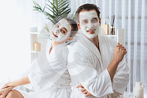 Blissful couple in bathrobe with facial cream mask. Quiescent