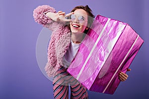 Blissful european woman in pink outfit holding sparkle present box. Laughing curly girl posing on p