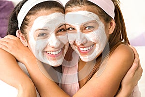 Blissful girls applying mask hugging each other