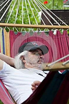 Blissful relaxation for the old man in the hammock. Serene old man enjoying a hammock. Contented old man finding solace in a