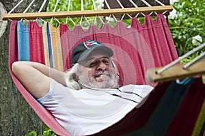 Blissful relaxation for the old man in the hammock. Serene old man enjoying a hammock. Contented old man finding solace in a