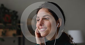 Blissful young woman wear wired earphones listens to favourite tune