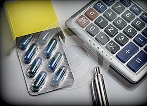 Blister pack of pills next to a calculator