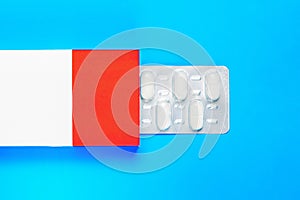 blister pack with pills in a red-white box on a blue background. copy space.