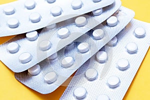 A blister pack of statins, pills tablets for lowering cholesterol on yellow background, prevention and treatment of