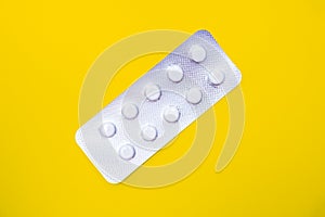 A blister pack of statins, pills tablets for lowering cholesterol on yellow background, prevention and treatment of photo