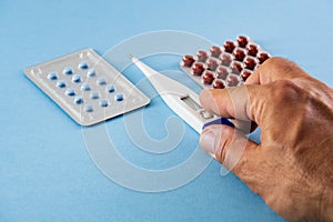 Blister packs of blue and brown pills and held electronic digital thermometer