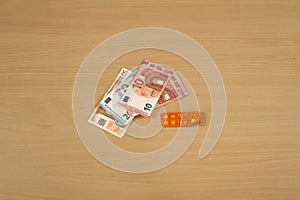 Blister packs with pill capsules appearing along with euro banknotes on a table