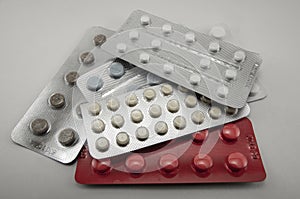 Blisters with round multi-colored tablets red yellow blue white on a light background close-up, antibiotics, vitamins, analgesic a