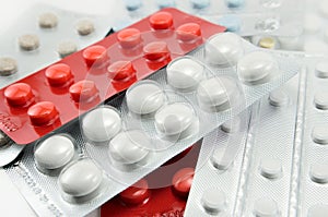 Blisters with round multi-colored tablets red yellow blue white  light background close-up macro, antibiotics, vitamins, analgesic photo