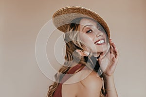 Blithesome long-haired girl in canotier laughing to camera. Studio photo of blonde woman in elegant boater hat..
