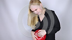 Bloating and flatulence concept. The woman holds a red balloon near the abdomen, which symbolizes bloating. Intestinal tract and d