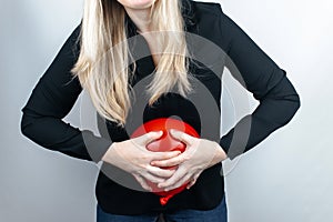 Bloating and flatulence concept. The woman holds a red balloon near the abdomen, which symbolizes bloating. Intestinal tract and d photo