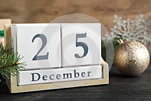 Block calendar and festive decor on black wooden table. Christmas countdown