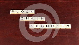 Block chain security spelled out in tiles on a cherry wood background