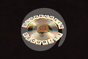 Block chain security spelled out in tiles circled around a CD and processor chip on a black background