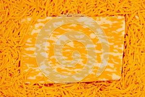 Block of cheese on shredded cheddar cheese background