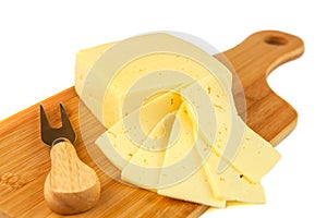Block of cheese and slices on cutting board with knife