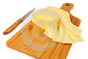 Block of cheese and slices on cutting board with a knife, isolated on white background