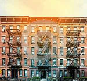 Block of classic old brick apartment buildings with windows and fire escapes in New York City