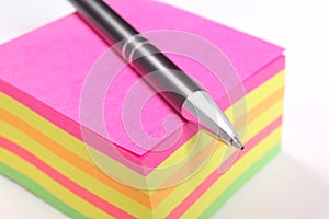 Block of colored sticky notes and a pen isolated on white background with copy space for your text