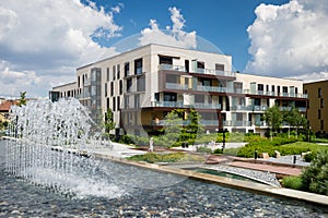 Block of flats in public park with water steam during hot summer day