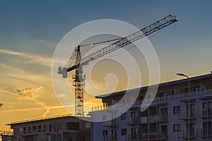 Block of flats under construction with crane at sunset sky, meeting deadline concept