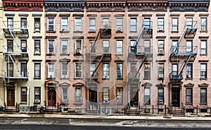 Block of historic apartment buildings crowded together on West 49th Street in the Hell`s Kitchen neighborhood of New York City