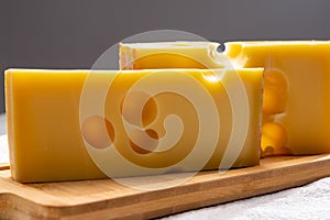 Block of Swiss medium-hard yellow cheese emmental or emmentaler with round holes