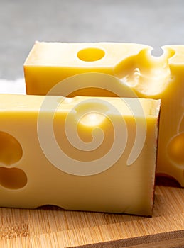 Block of Swiss medium-hard yellow cheese emmental or emmentaler with round holes