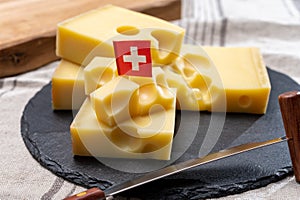 Block of Swiss medium-hard yellow cheese emmental or emmentaler with round holes and cheese knife