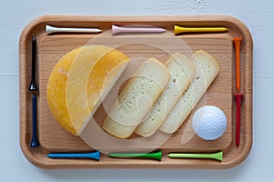 Block of tasty cheese on cutting board with a knife and golf tee