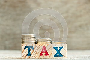 Block in word tax with coin in downtrend on wood background