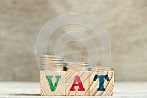 Block in word VAT Value added tax with coin in down trend on wood background