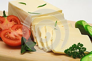 Block yellow cheese slices on wooden cutting board