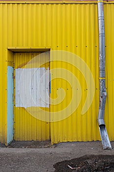 blocked entrance to a yellow colored building next to a drain pipe