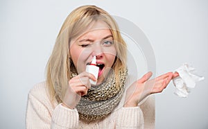 Blocking a nostril. Cute woman nursing nasal cold or allergy. Unhealthy girl with runny nose using nasal spray. Sick