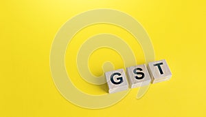 Blocks with letters GST Goods and Services Tax on a yellow background. State financial policy to regulate tax collection rules photo