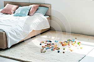 Blocks near bed with white bedding, blue and pink pillows