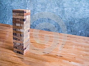 Blocks wood game or jenga game on wood table with cement wall ba