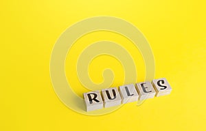 Blocks with the word Rules on yellow background. Laws and community ethics norms. Terms of the contract and the obligations