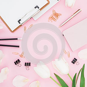 Blogger concept with copy space. Frame with tulips flowers, clipboard and clips on pink background. Flat lay, top view