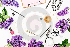 Blogger or freelancer composition with clipboard, notebook, cosmetics, branches of lilac flowers and accessories on white backgrou