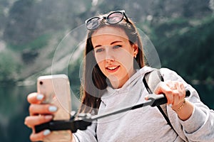 Blogger girl. Young female travel photographer with smartphone on summer mountain rock nature background. Freedom