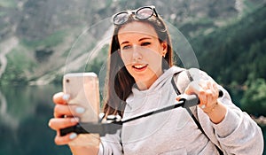 Blogger girl. Young female travel photographer with smartphone on summer mountain rock nature background. Freedom