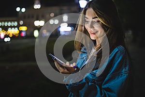 Blogger hipster using in hands gadget mobile phone. Woman pointing finger on blank screen smartphone on background bokeh light in