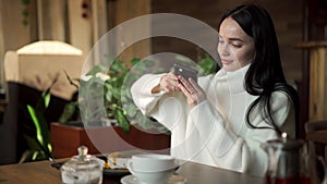 Blogger influencer eat cake at cafe. Young lady using mobile phone taking a photo of her food for social media