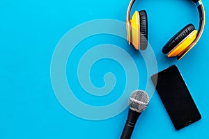 Blogger, journalist or musician work space with microphone, telephone and headphones on blue background top view mock-up