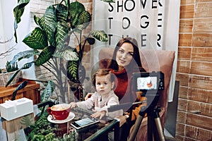 Blogger mother and her little daughter have fun together with the vlog camera. Young parenting blogger recording a video